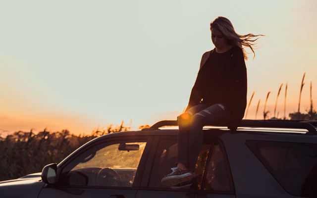 Girl sitting on top of car